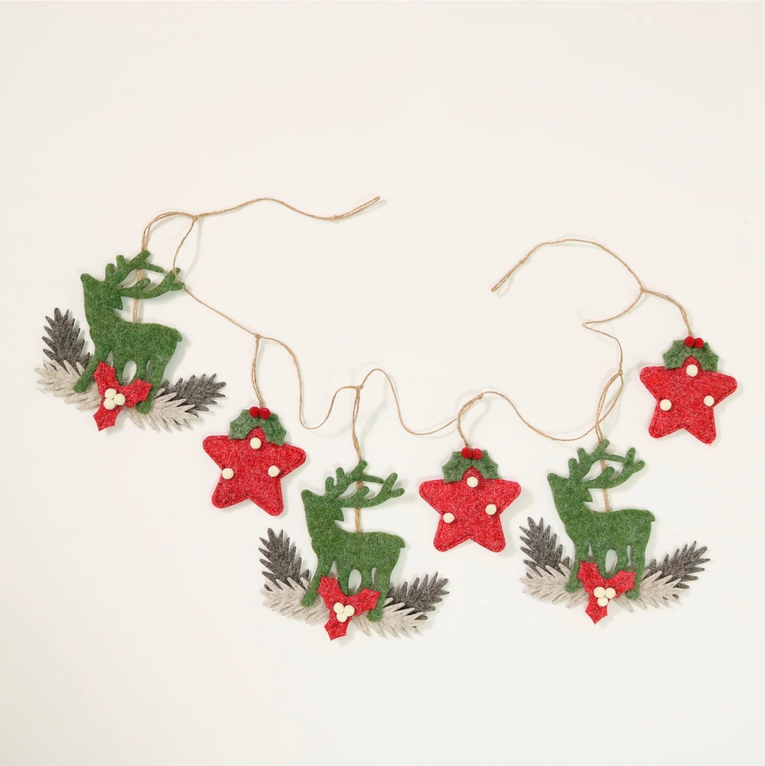 A festive Christmas garland featuring felt cutouts of green reindeer, red glittery stars, and holly with pine branches, strung on natural jute twine against a plain off-white background.