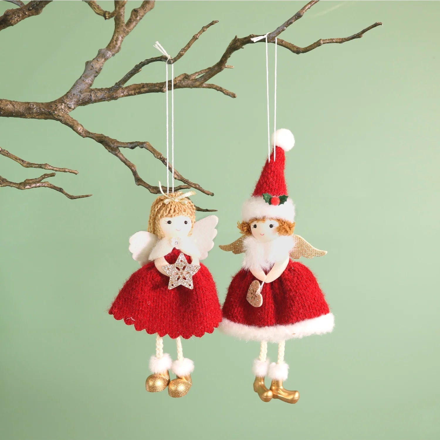 Two knitted angel ornaments hanging from branches against a light green background