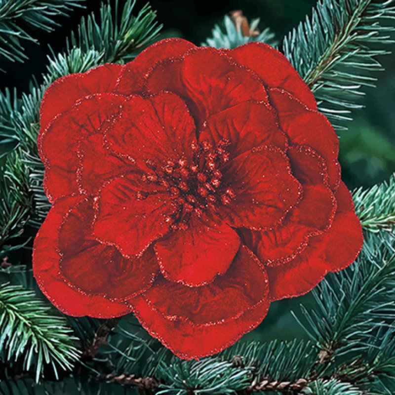 A large, vibrant red artificial flower with glittery edges, displayed on a green pine branch.