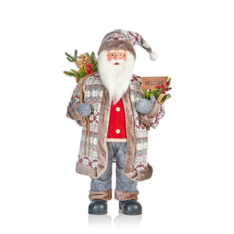 A festive Santa Claus figurine wearing a patterned knit coat and hat, with a white beard, red shirt, gray pants, and black boots, holding a small 'WELCOME' sign and evergreen branches.